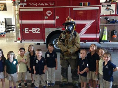 A group of children standing in front of a fire truck that says e-82