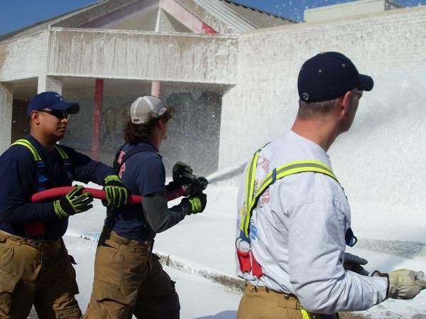 A group of firefighters are spraying foam on a building