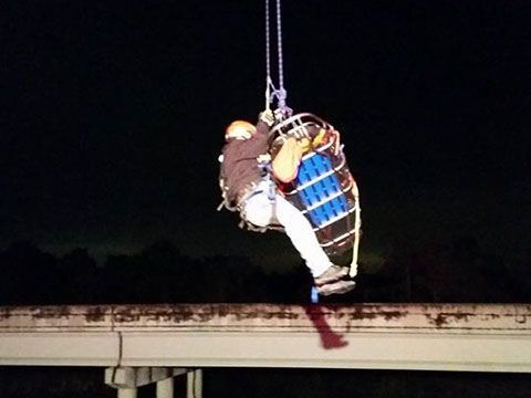 A fire fighter is holding onto a stokes basket during a high angle rescue.
