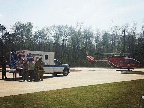 A group of people standing next to an ambulance parked next to a life flight helicopter.