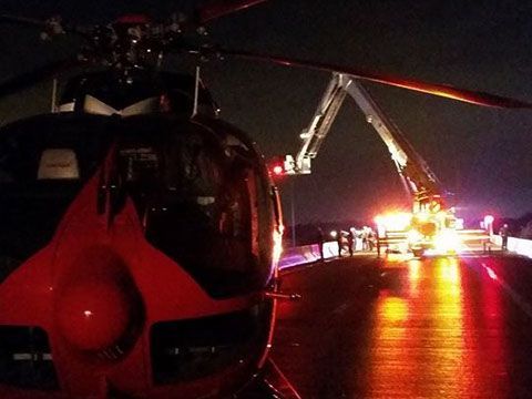 A red helicopter is parked on the side of a road at night