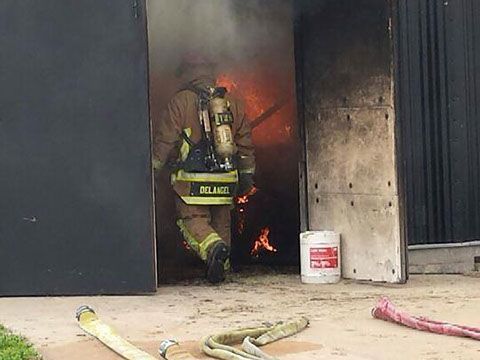 A fireman is standing in front of a fire in in front of a training building