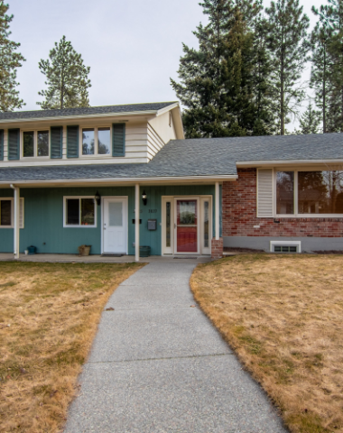 A blue house with a red door is next to a brick house