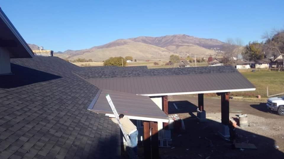 A house with a roof that has shingles on it and mountains in the background.