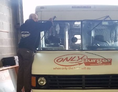 A person in a dark hoodie stands on the bumper of an 