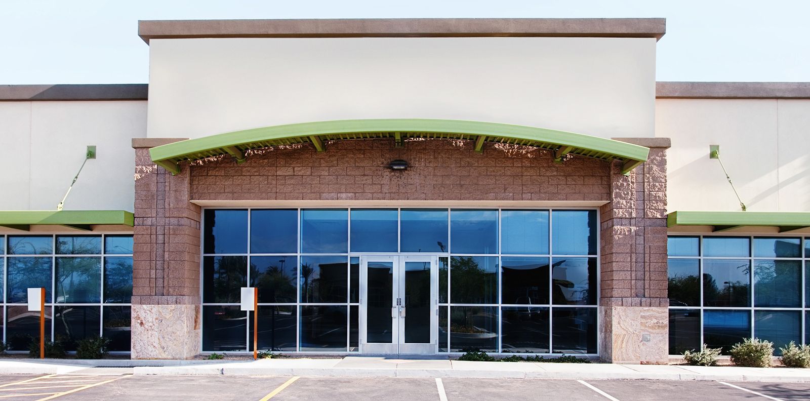 Storefront with glass doors and windows, brick facade, and green awning at a shopping center
