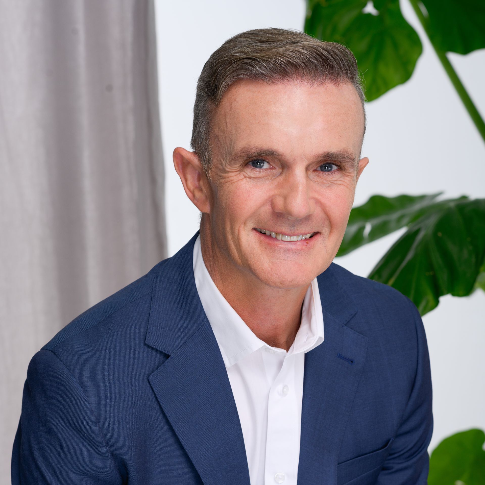 A man in a white shirt is sitting in front of a plant.
