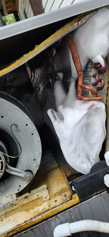 Cluttered under-sink cabinet with a hose, white plastic bag, and a metal fan or appliance part