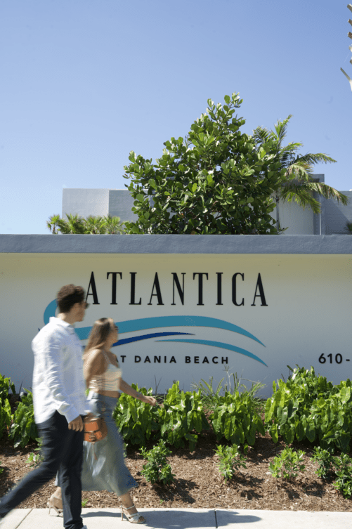 A man and woman walk past a sign that says atlantica