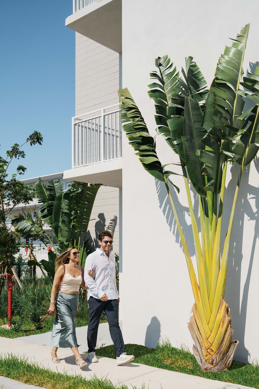 A man and a woman are walking down a sidewalk in front of a building.