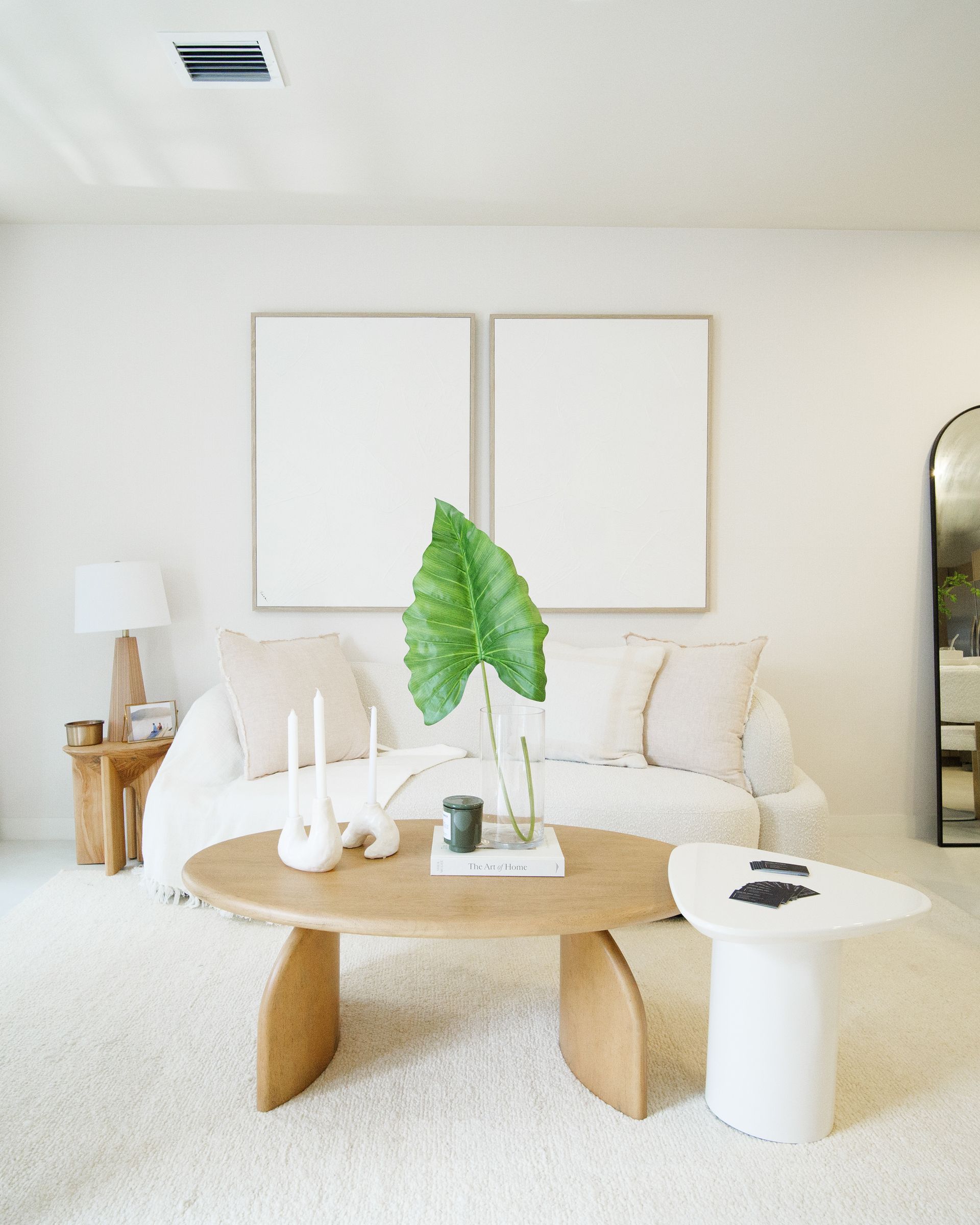A living room with a dining table and chairs and a large mirror.