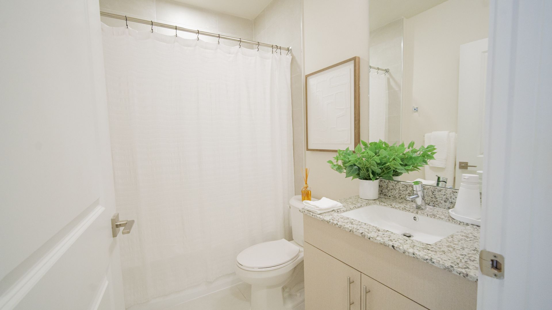 A bathroom with a toilet , sink , mirror and shower curtain.
