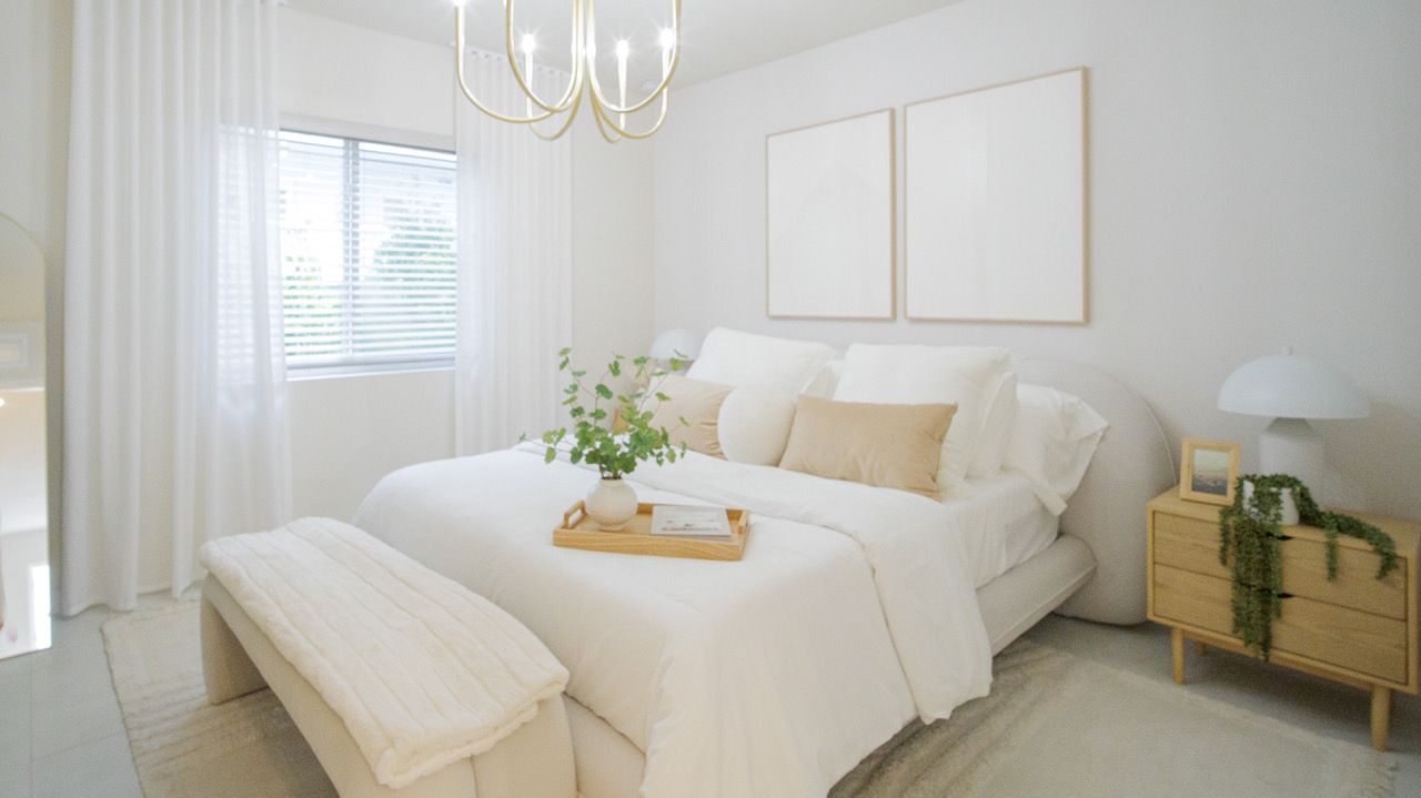 A bedroom with a bed , bench , nightstand , and chandelier.