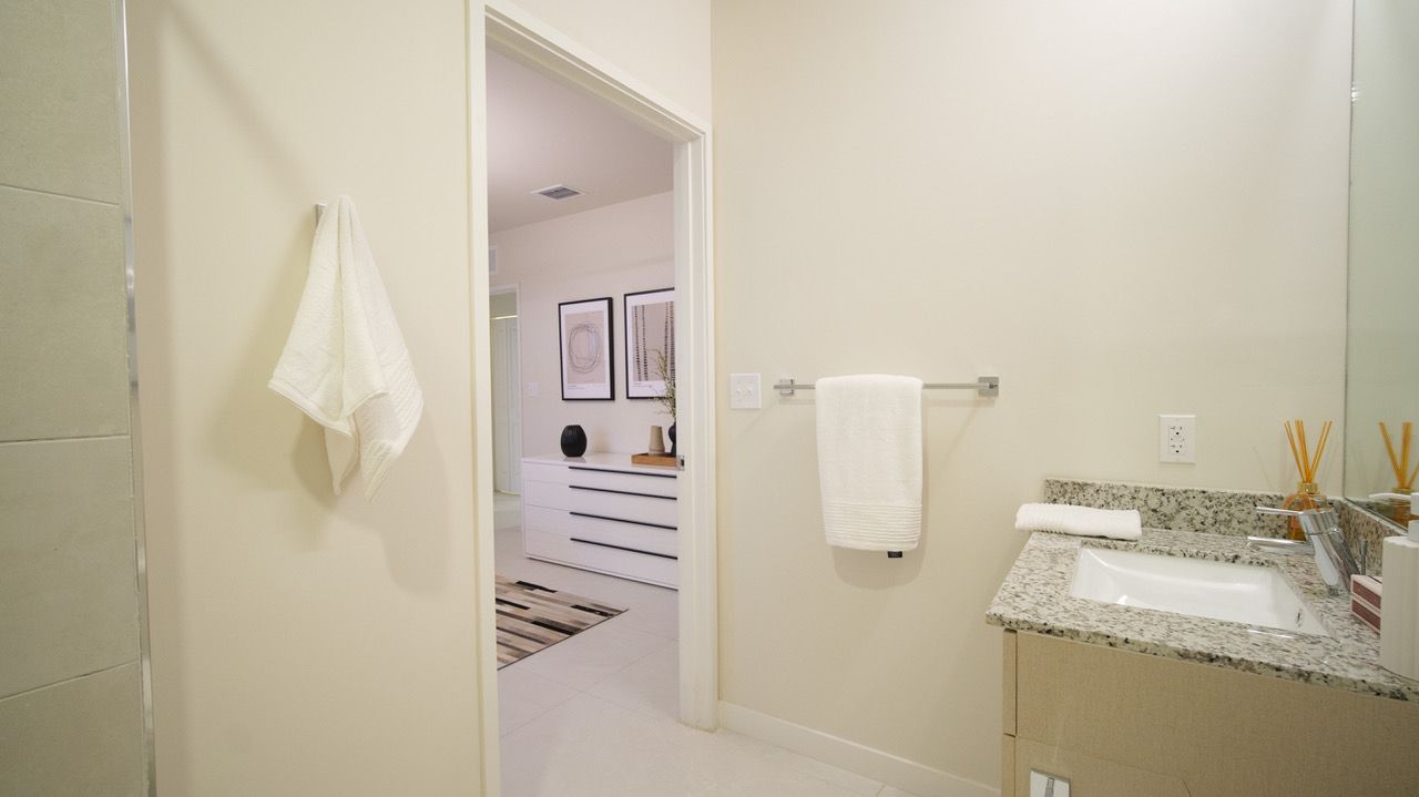 A bathroom with a sink , mirror and walk in shower.