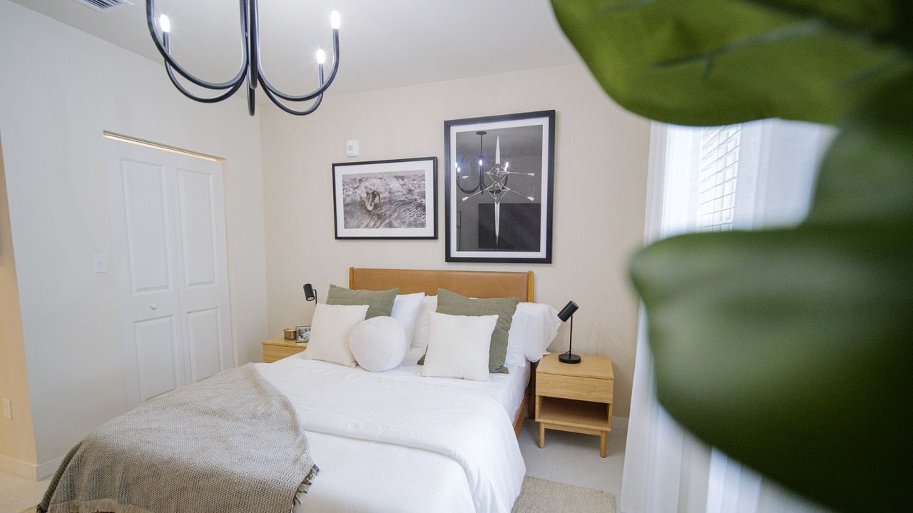 A bedroom with a large bed , nightstands , and a chandelier.