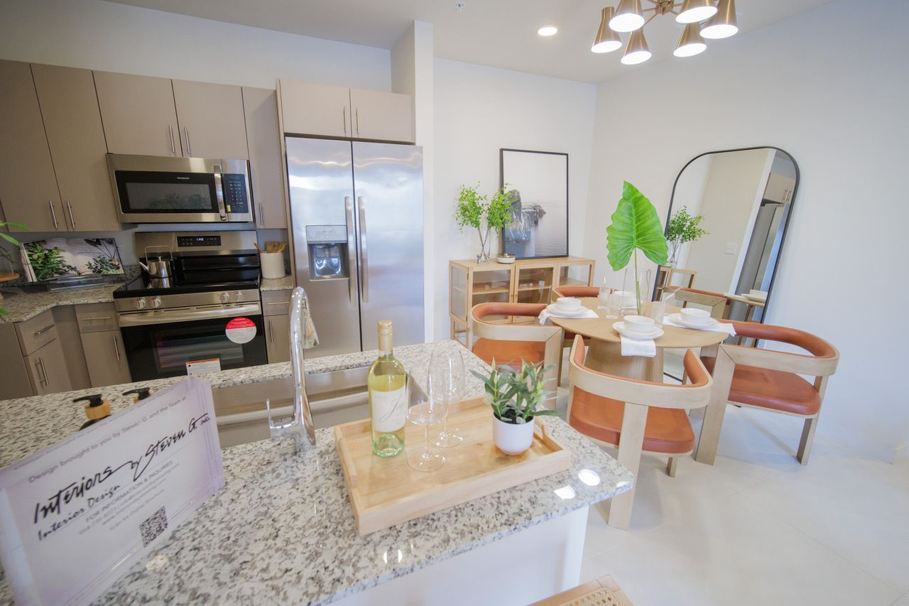 A kitchen with stainless steel appliances , granite counter tops , a dining table and chairs.