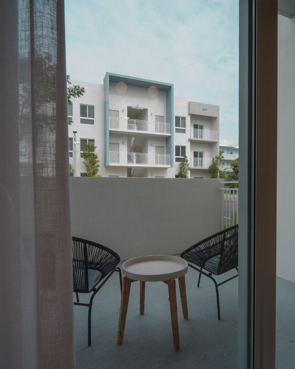 A balcony with a table and chairs and a building in the background