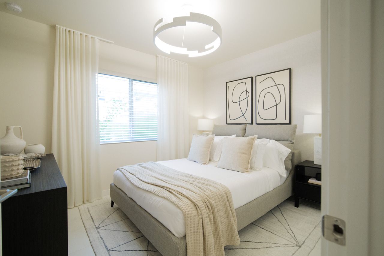 A bedroom with a bed , dresser , nightstand and window.