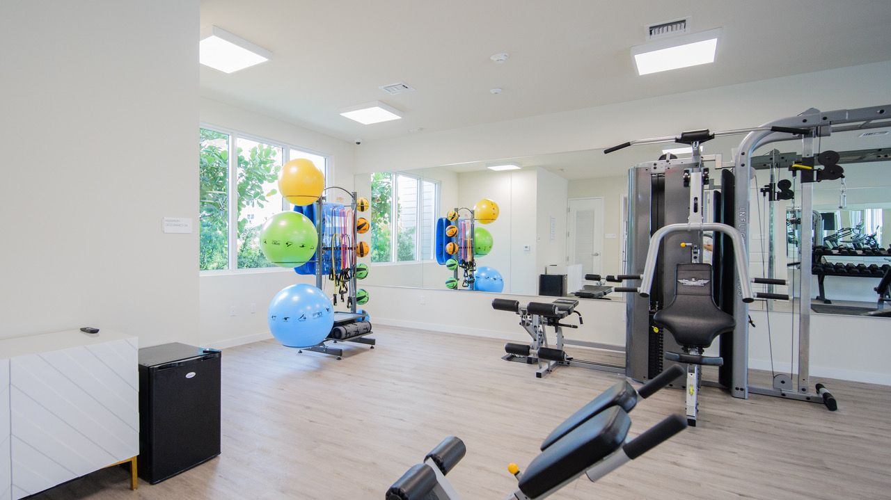 A gym with a lot of equipment and a lot of windows.