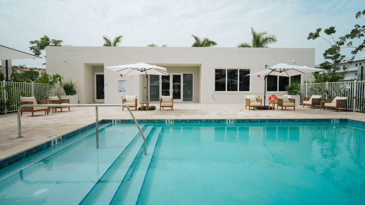 A swimming pool with chairs and umbrellas in front of a building.