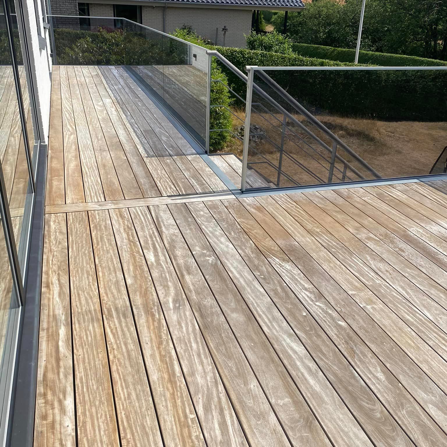 Et træterrasse med glasrækværk og trapper