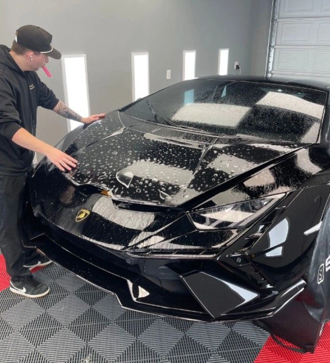 a man applying paint protection film on the hood of the car