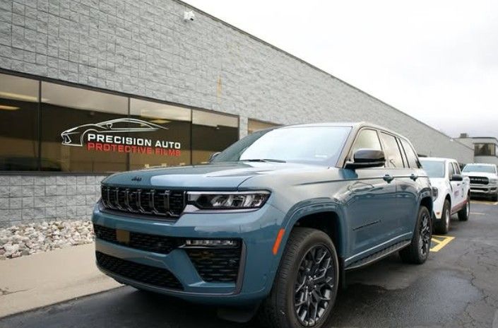 Blue SUV parked outside Precision Auto dealership with a white truck behind it.