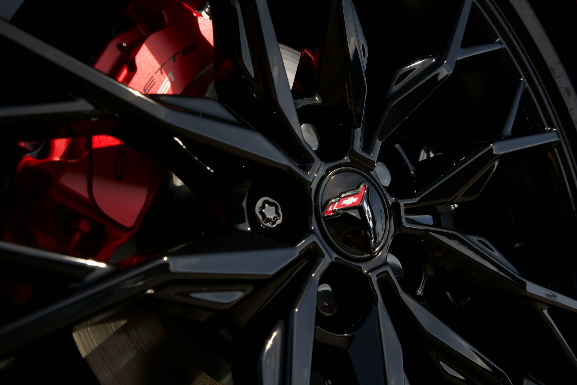 A close up of a black car wheel with red brake calipers.