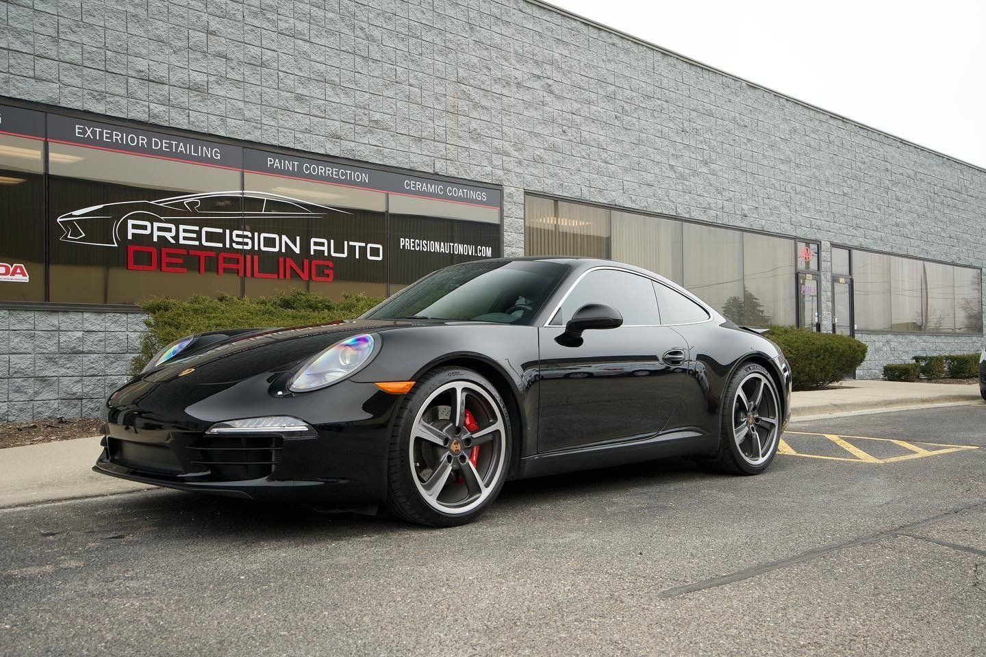 A black porsche 911 is parked in front of a building.