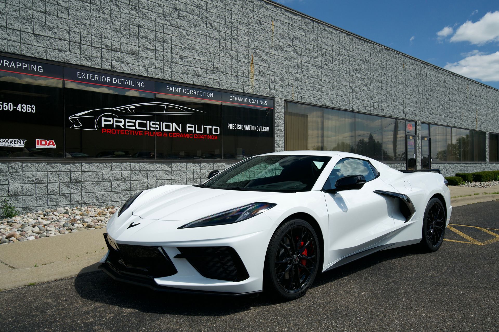 A white sports car is parked in front of a building.