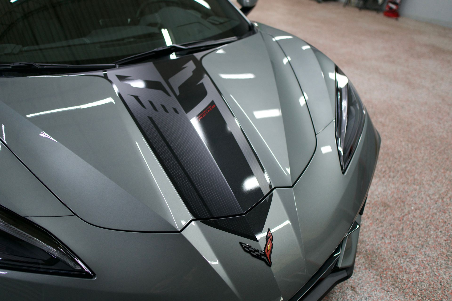 A silver sports car with a black stripe on the hood
