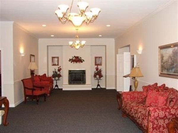 Spacious room with fireplace, chandeliers, red furniture, and dark carpet.