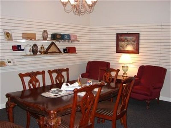 Dining room with table, chairs, display shelves holding urns, and two red armchairs.