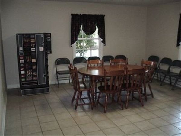 Room with a round table and chairs, a vending machine, and chairs lining the walls.