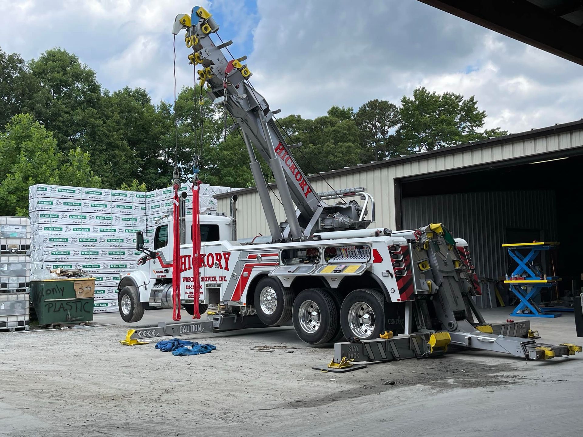 A tow truck with a crane attached to it is parked in front of a building.