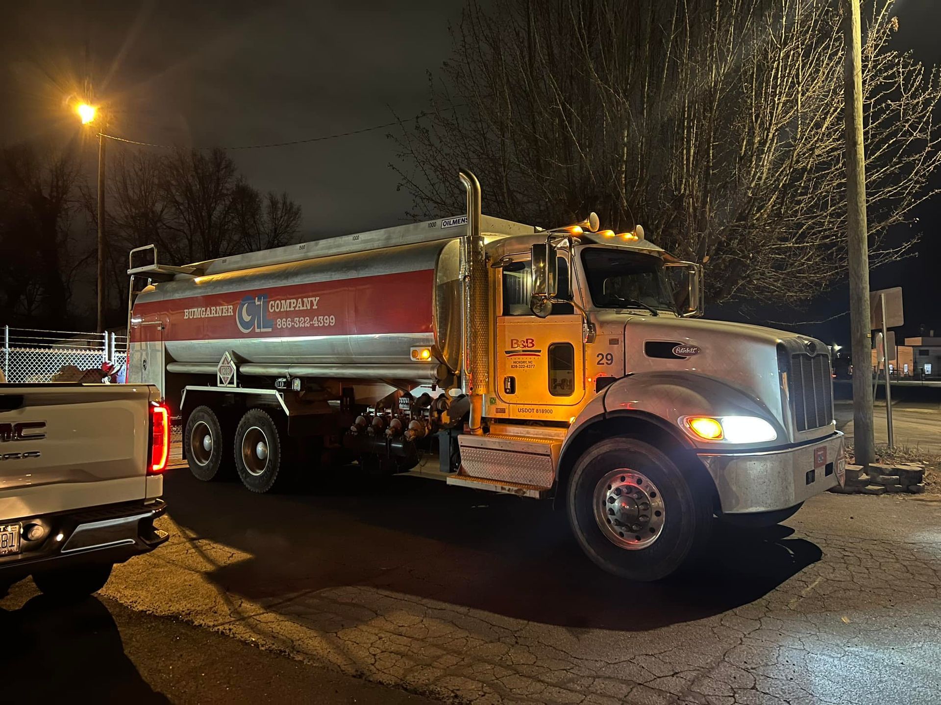 A large tanker truck is parked in a parking lot at night.
