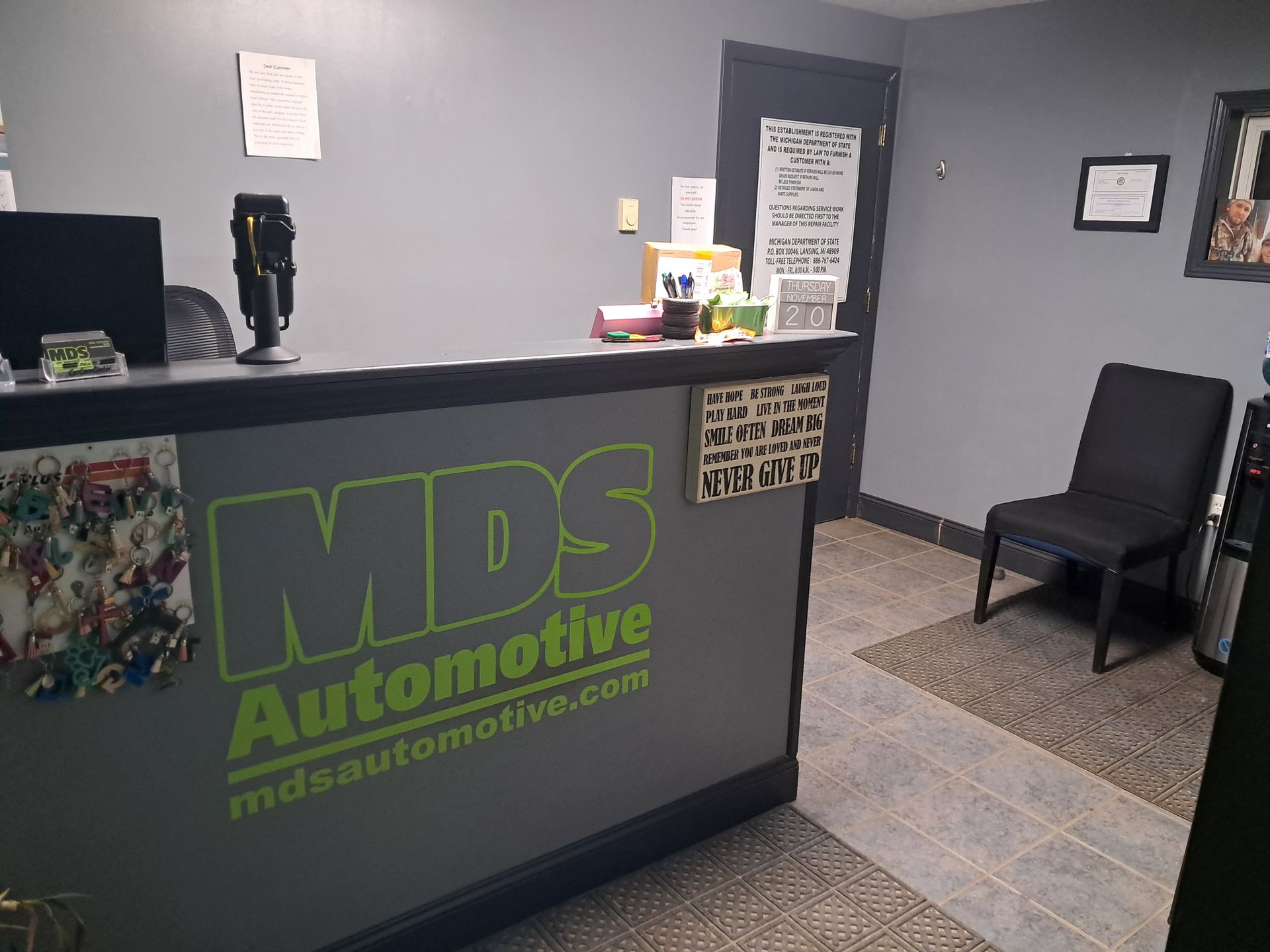 Waiting room with chairs, portable AC unit, small fridge, and a sleeping black dog. | MDS Automotive