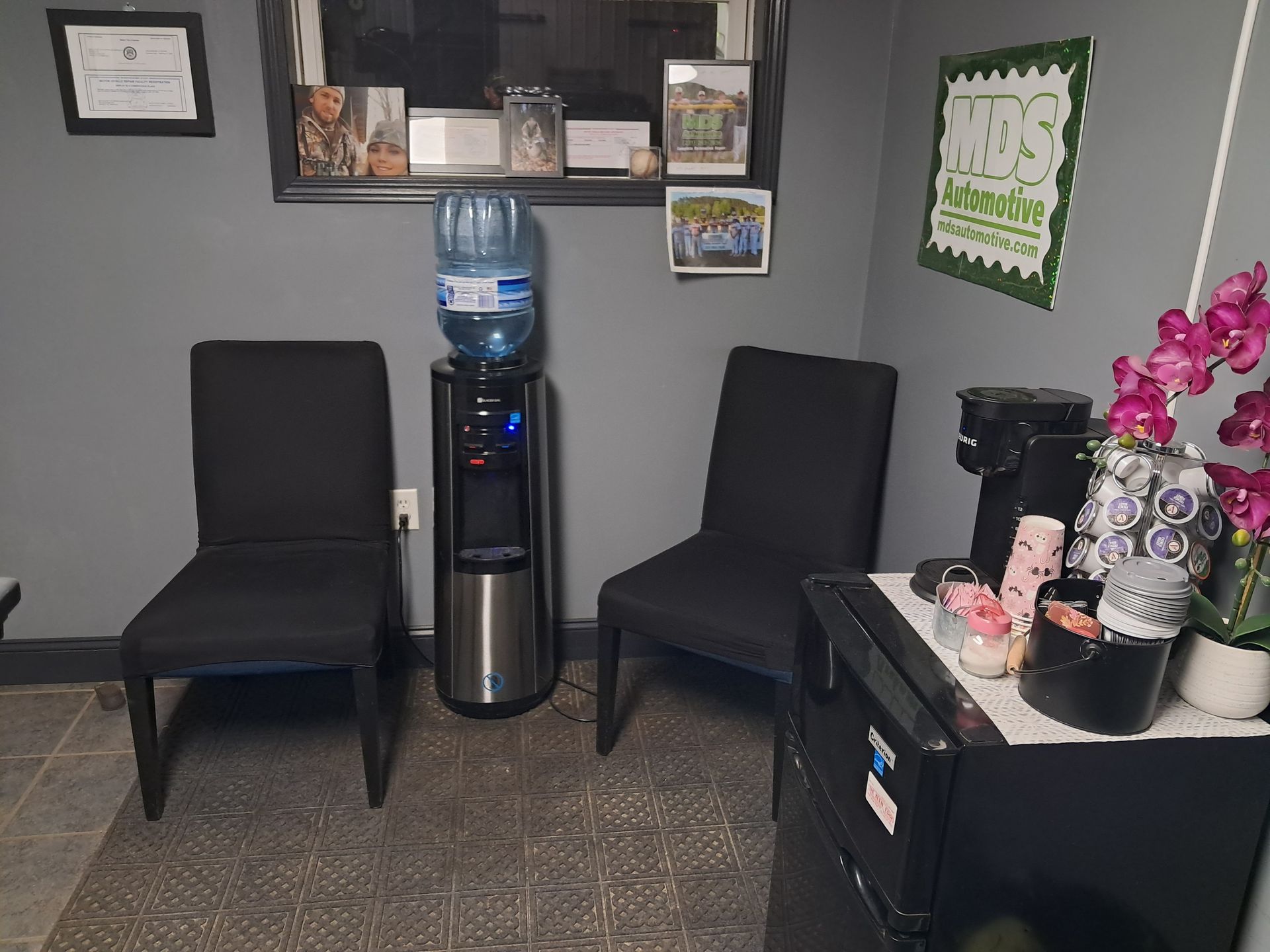 Waiting room with chairs, rug, window, and cabinet with snacks. | MDS Automotive