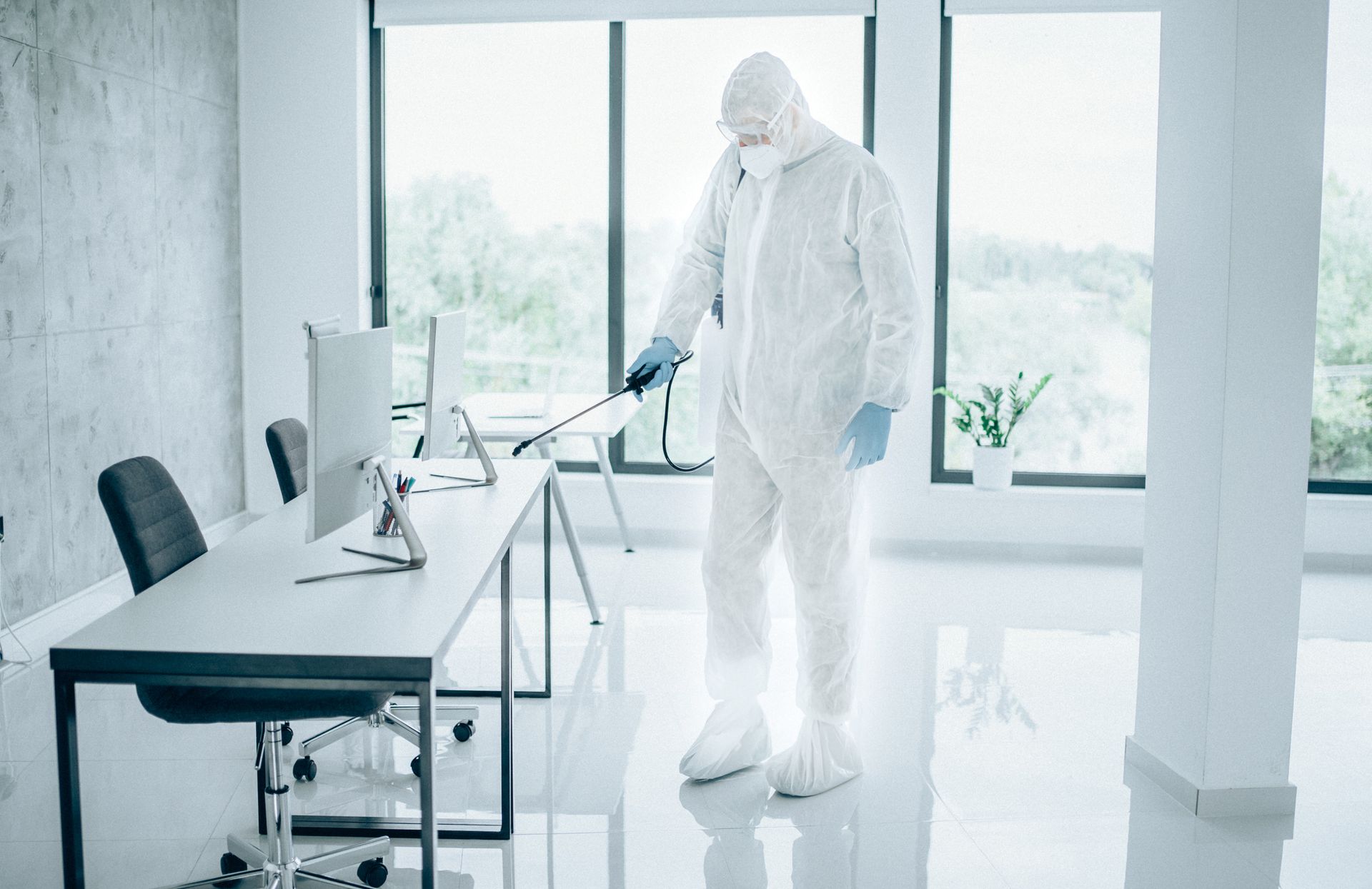 Un uomo con una tuta protettiva sta disinfettando un ufficio.