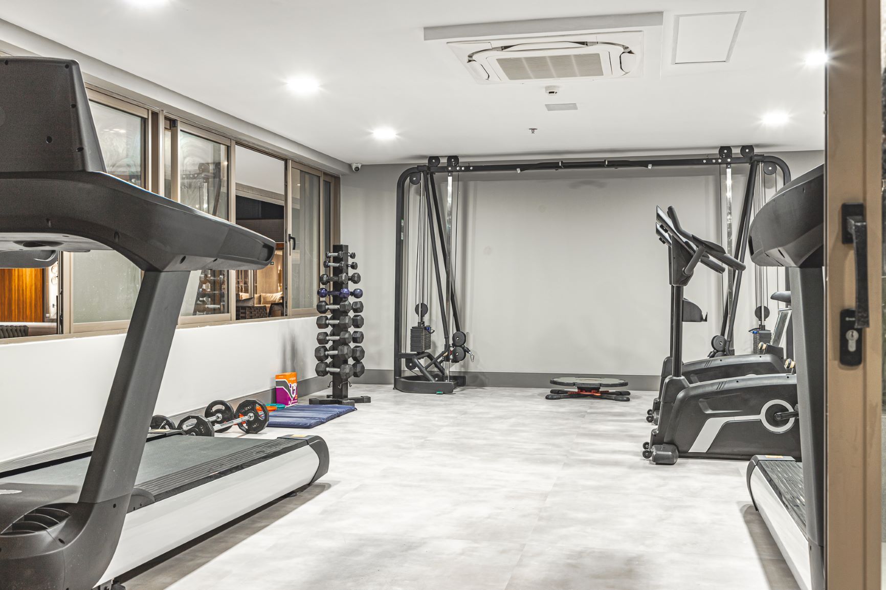 Uma academia com esteiras, elípticos, halteres e outros equipamentos de exercício.