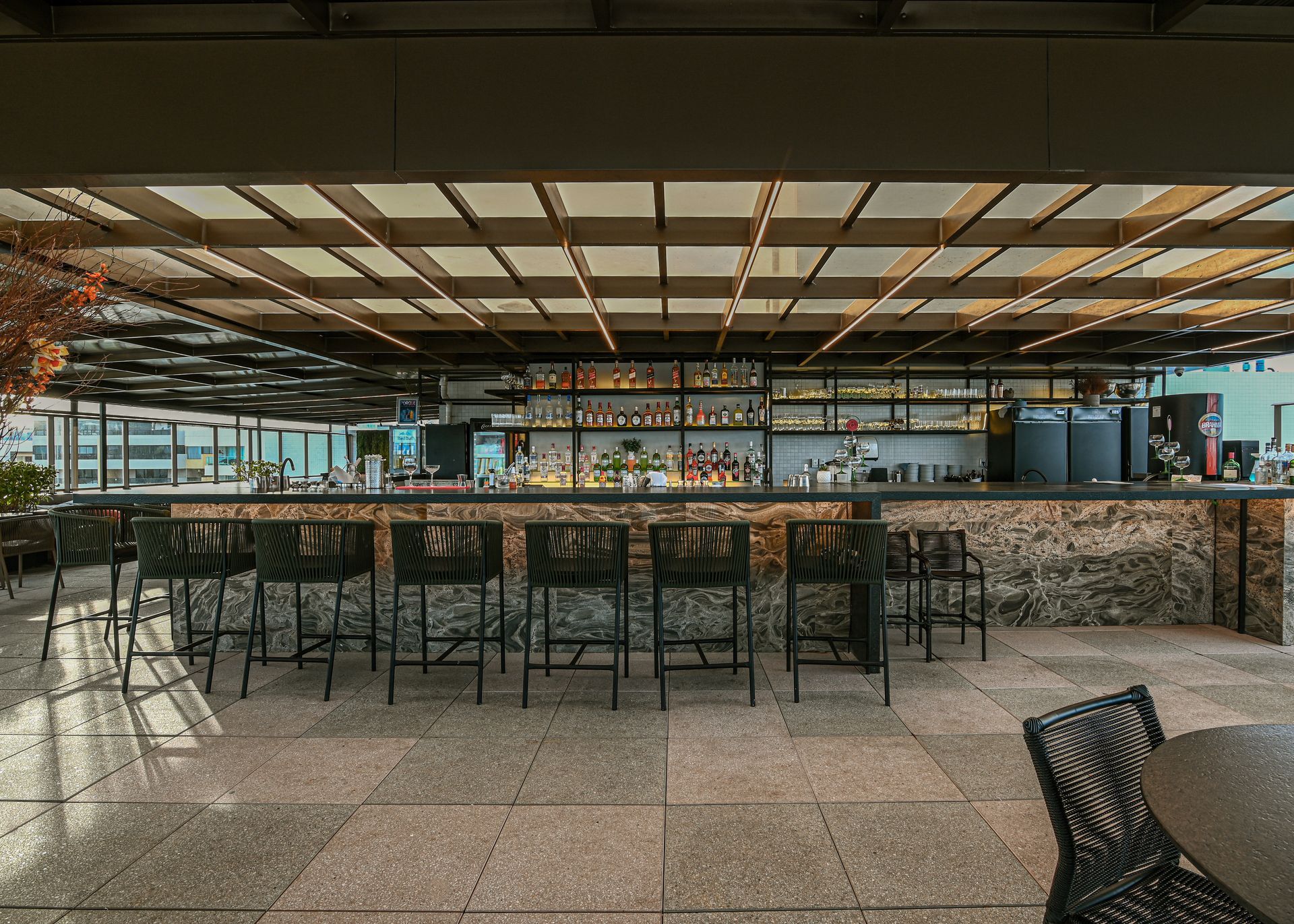 Um bar com muitas cadeiras e mesas em um restaurante.