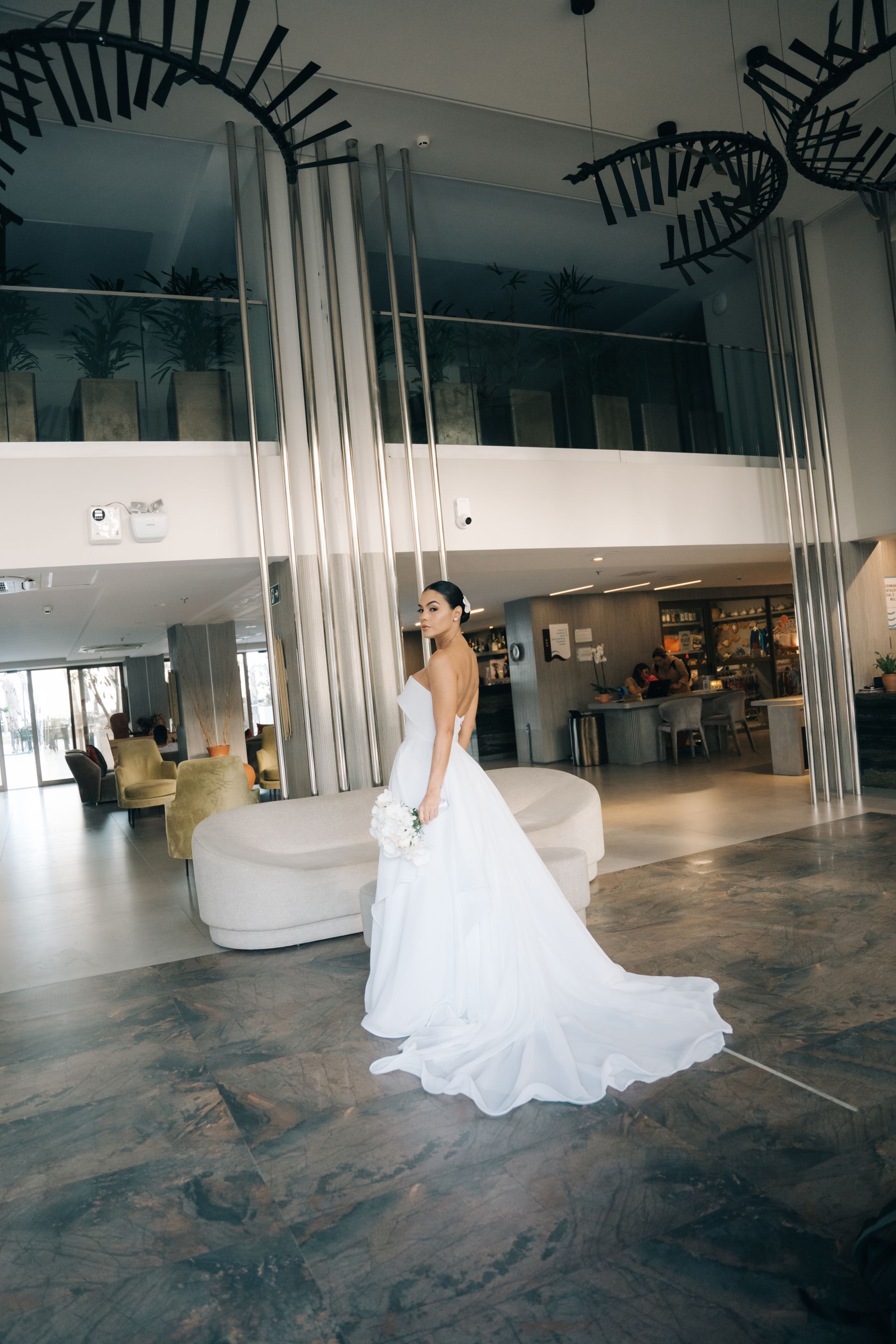 Uma mulher vestida de noiva está parada no saguão de um hotel.