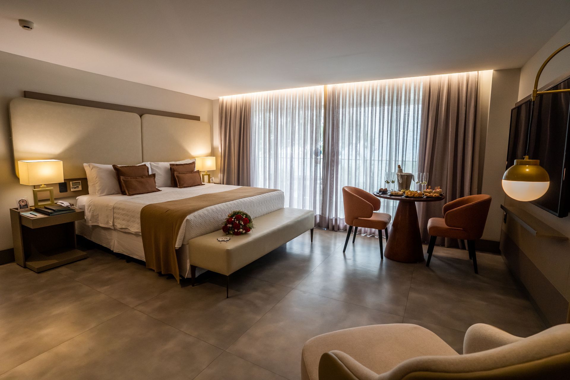 Um quarto de hotel com uma cama king size, cadeiras e uma mesa.