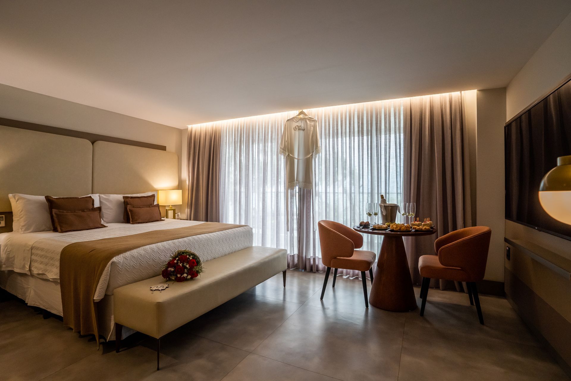 Um quarto de hotel com uma cama king size, cadeiras e uma mesa.