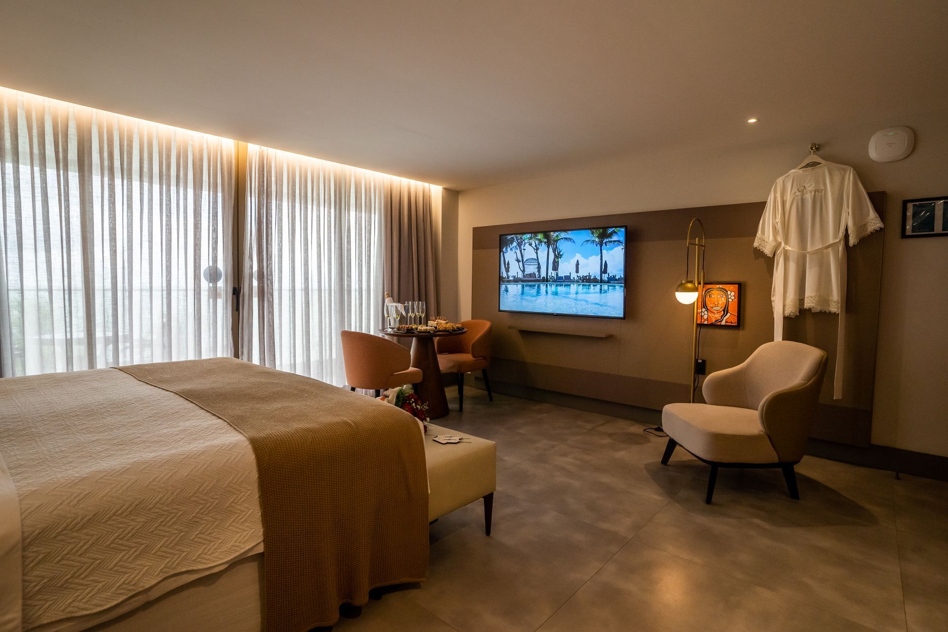 Um quarto de hotel com uma cama grande, cadeiras e uma TV de tela plana.