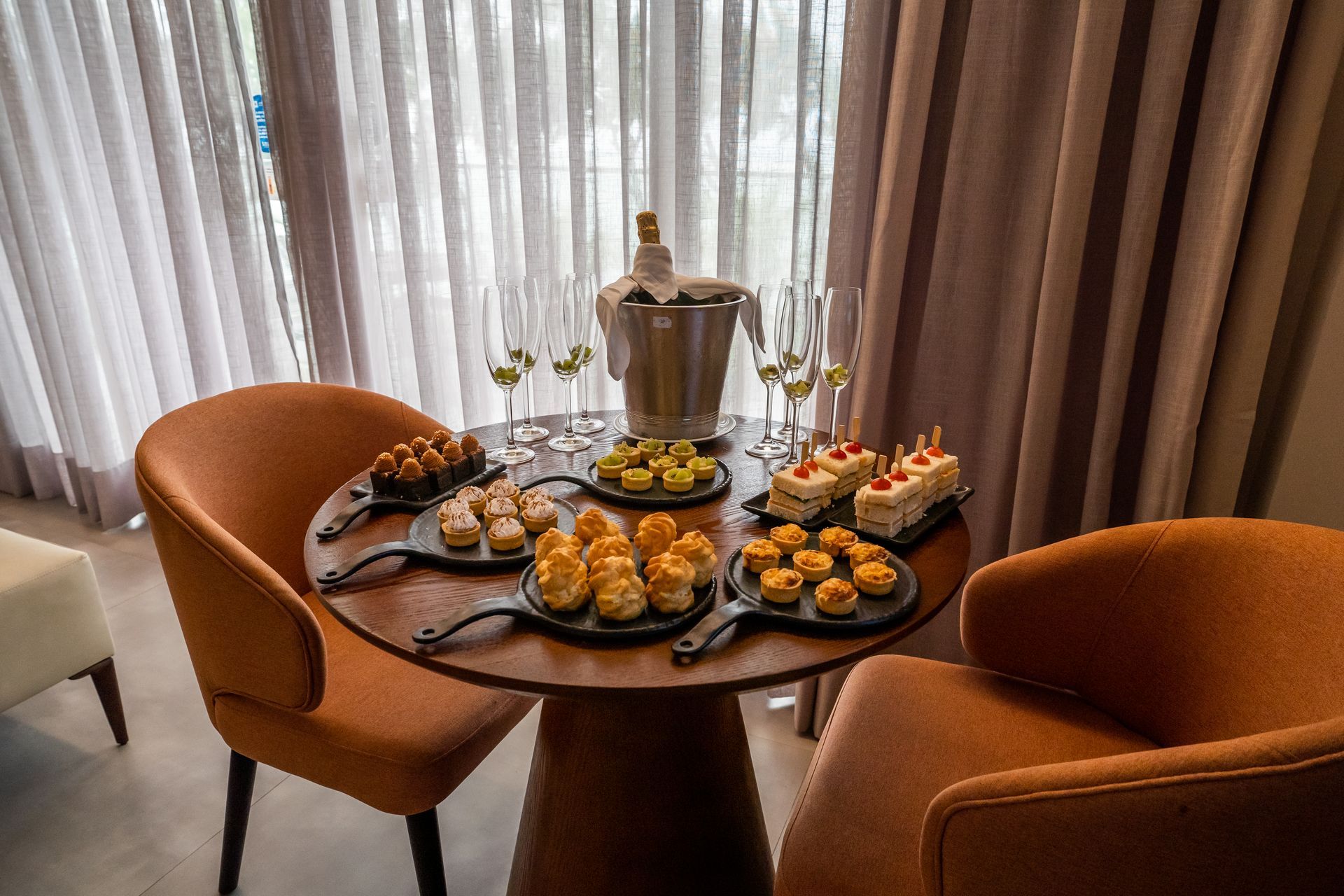 Uma mesa com pratos de comida e um balde de champanhe em um quarto de hotel.