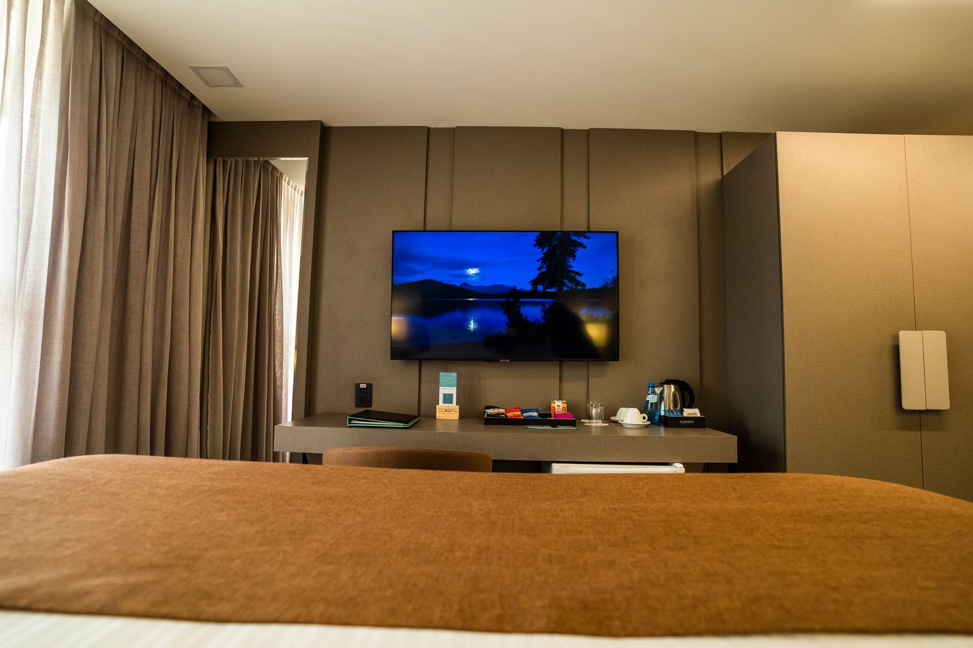 Um quarto de hotel com uma grande TV de tela plana na parede