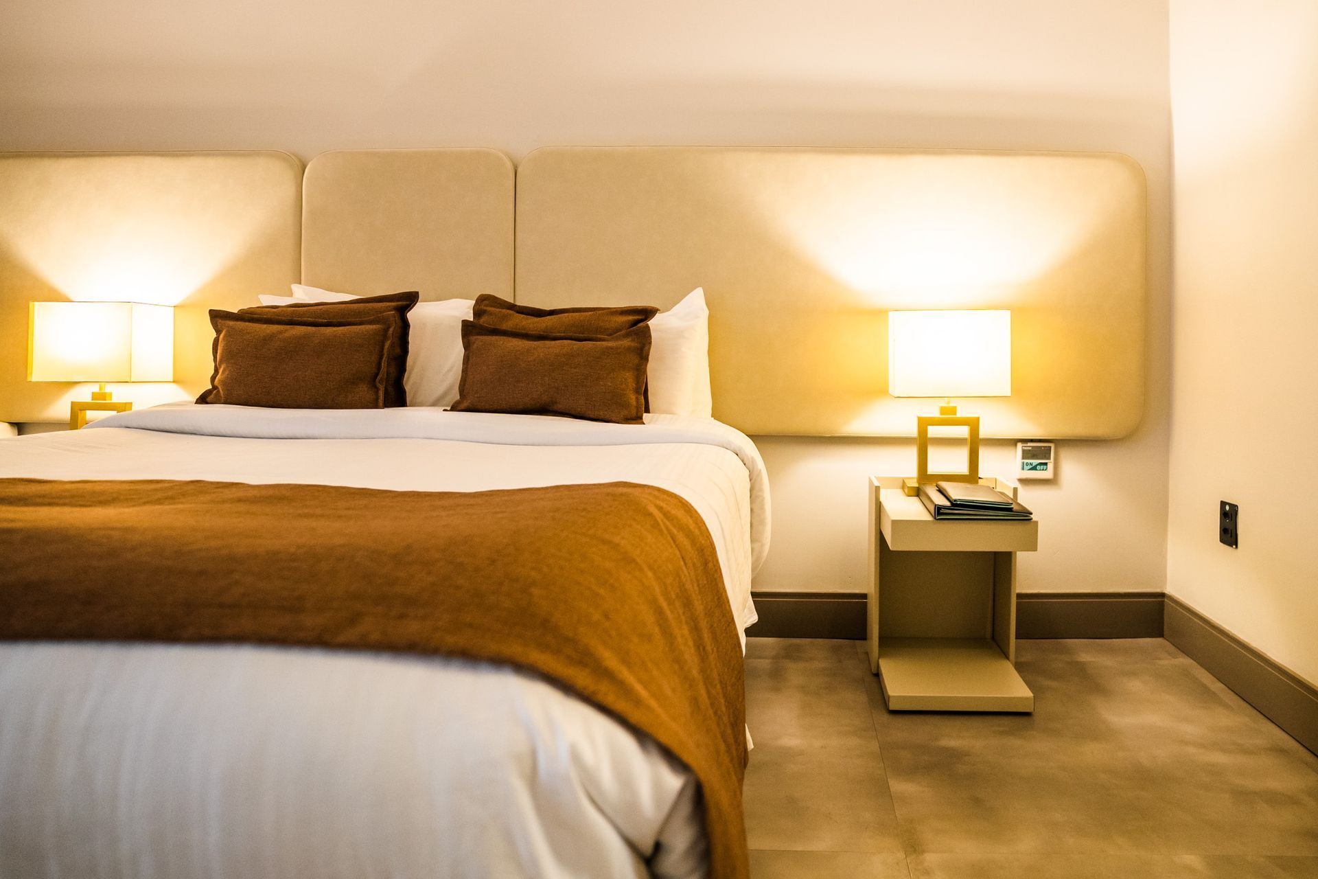 Um quarto de hotel com uma cama king size e duas lâmpadas.