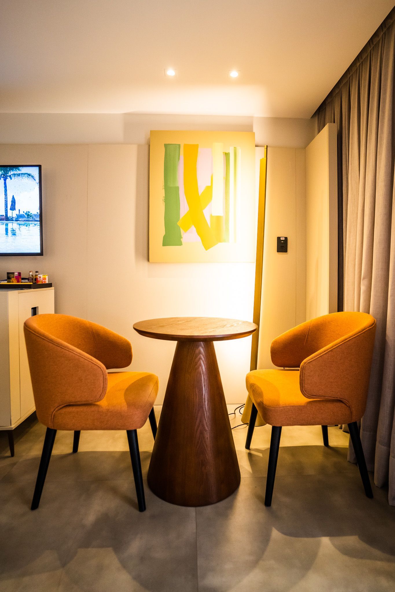 Uma sala com duas cadeiras e uma mesa com uma pintura na parede.