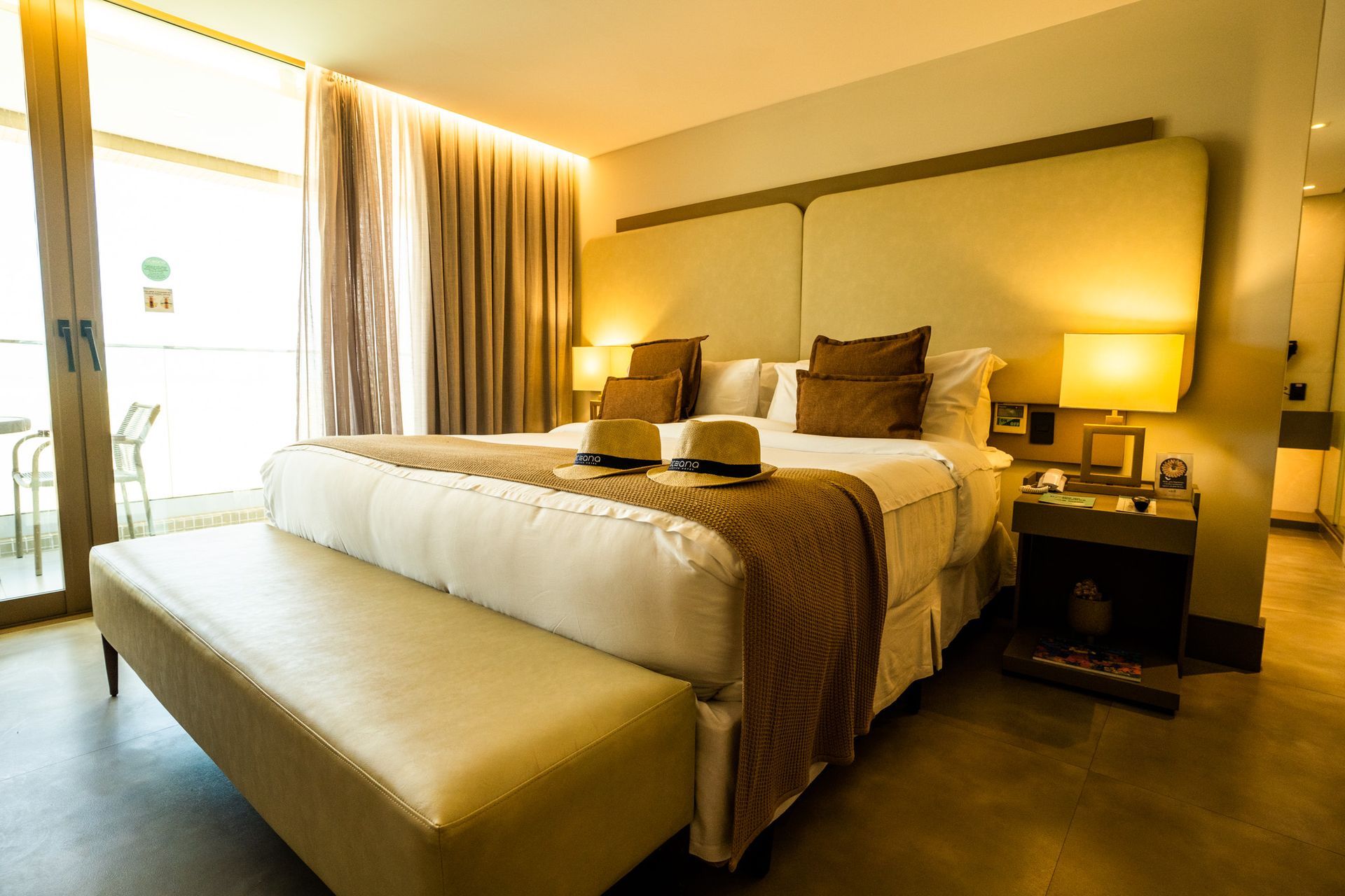 Um quarto de hotel com uma cama king size e um banco.